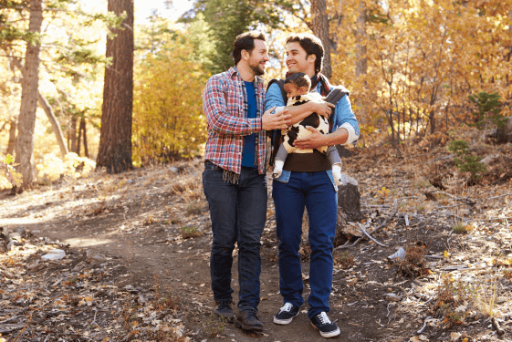 benefits Two men walking outside with a baby.