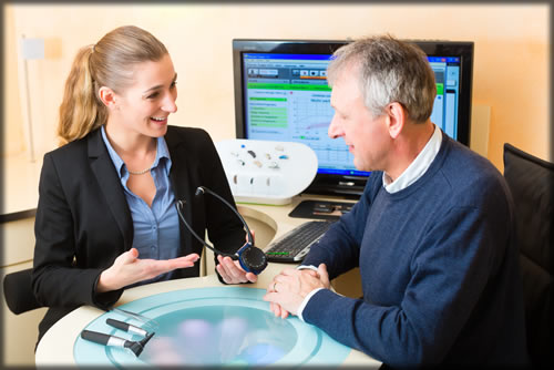 A amn and woman at a table holding an assistive listening device.