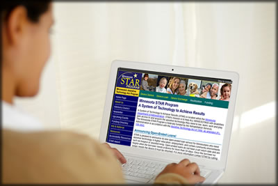 A person with a disability at a computer. The Minnesota Star program website is on the screen. 