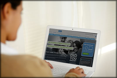 A woman sitting at a computer that shows www.stopthinkconnect.org on the screen.