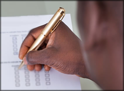 A man's hand holding a pen filling out a checklist.