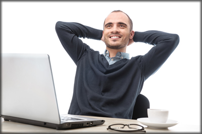 A smioling man sitting at a laptop.
