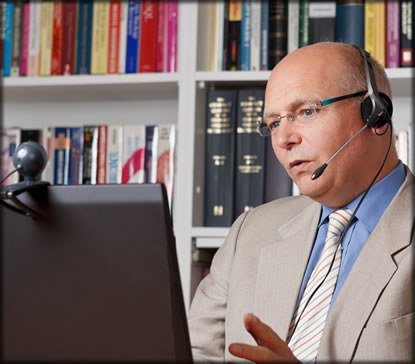 Man sitting at a laptop wearing a headset.