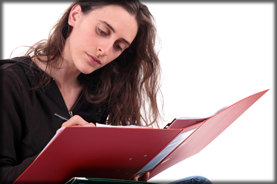 A woman writing in a three ring binder.