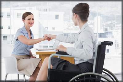 Person with a disability at a desk with a business person. 