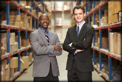 Two men in suits standing in a warehouse.