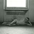 Naked resident lying on floor by radiator
